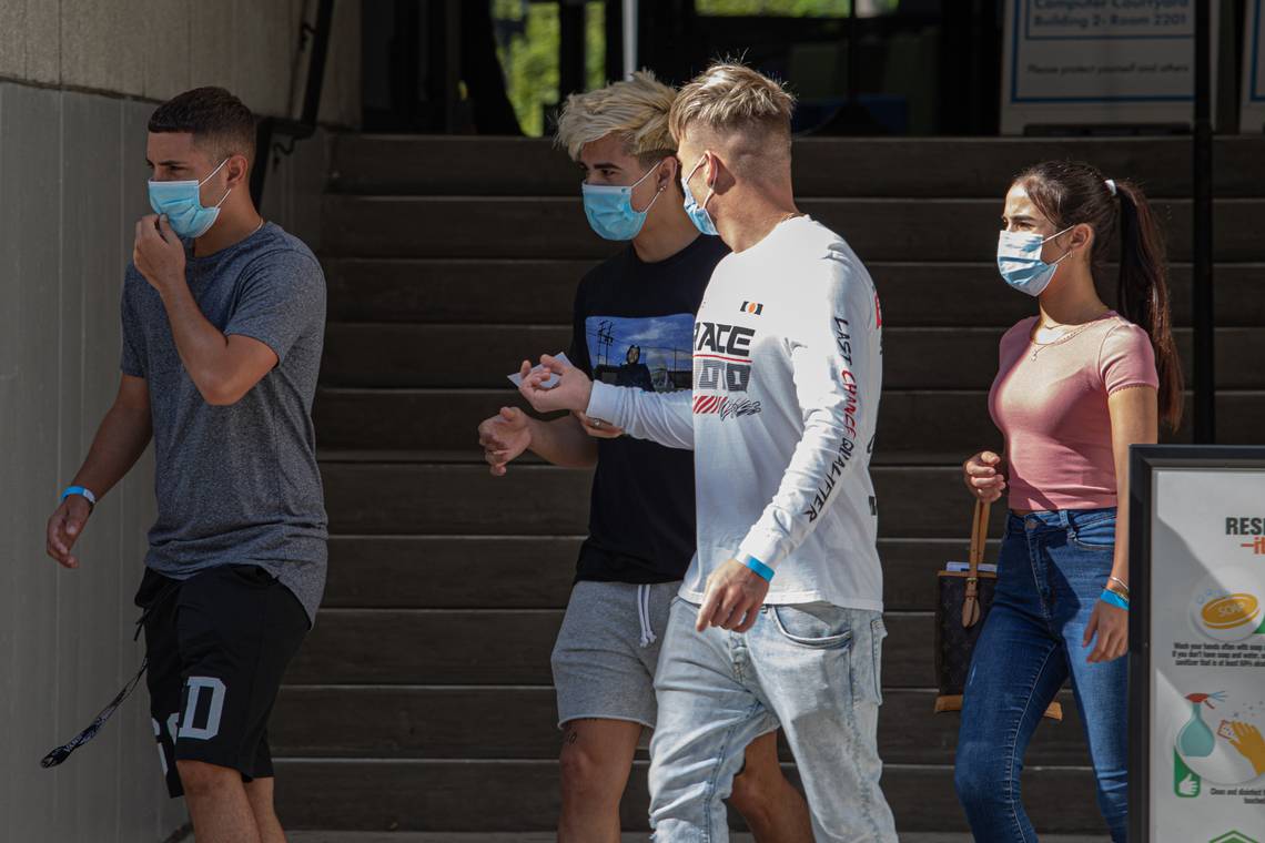 students walking on campus while wearing masks, interacting