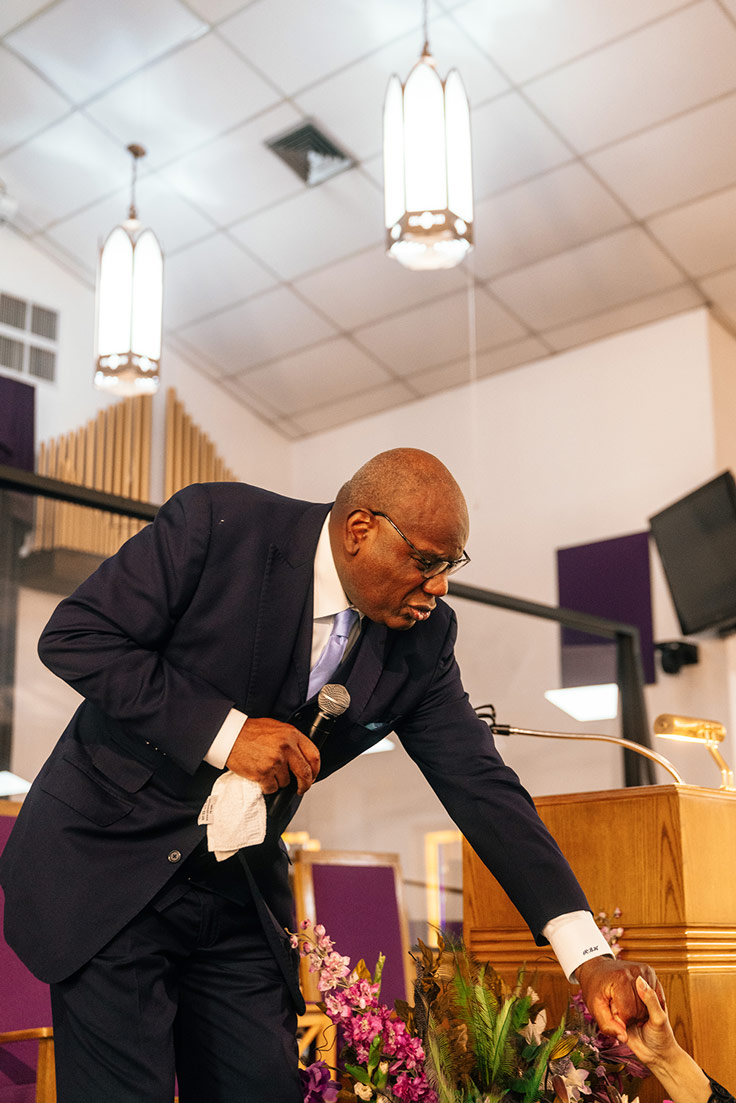 a man reaching down form a stage to hold another hand