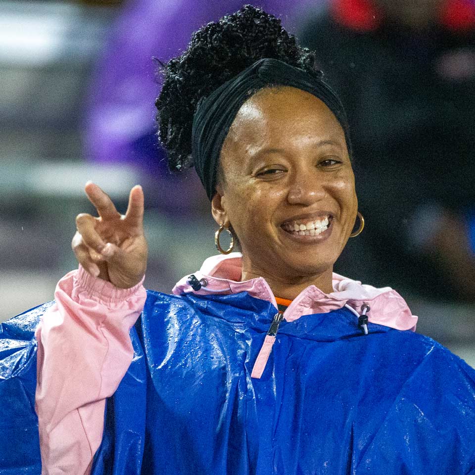 woman with rain poncho smiling and holding fingers like rattle snake