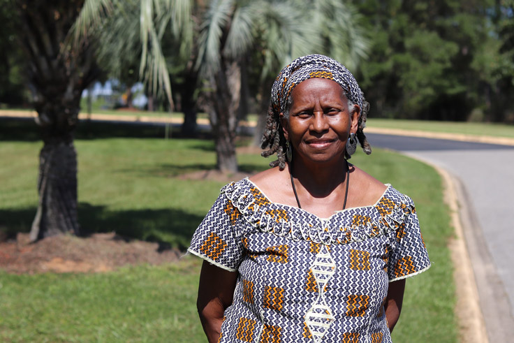 a Black woman standing with her hands behind her back