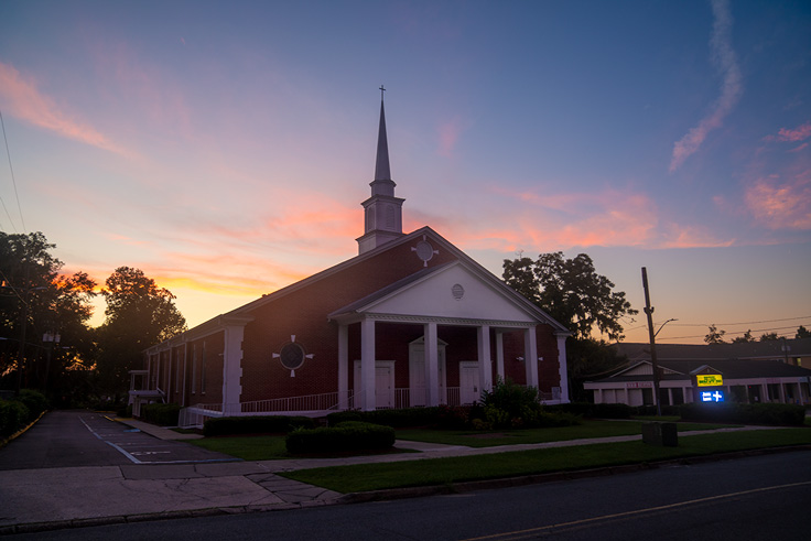 church with sun setting behind it