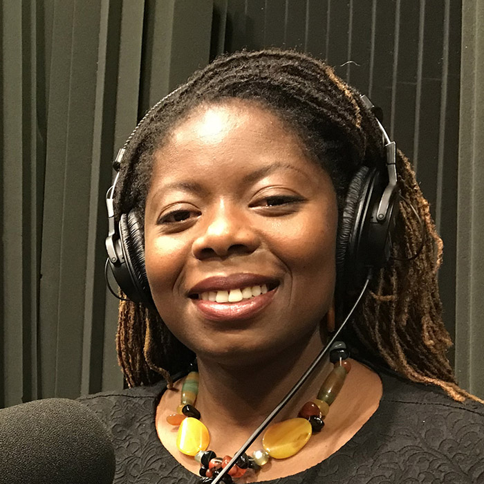 Abena sitting in the studio by the microphone with headphones on