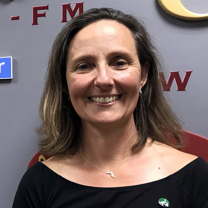 Aliki smiling in front of the WFSU radio station sign