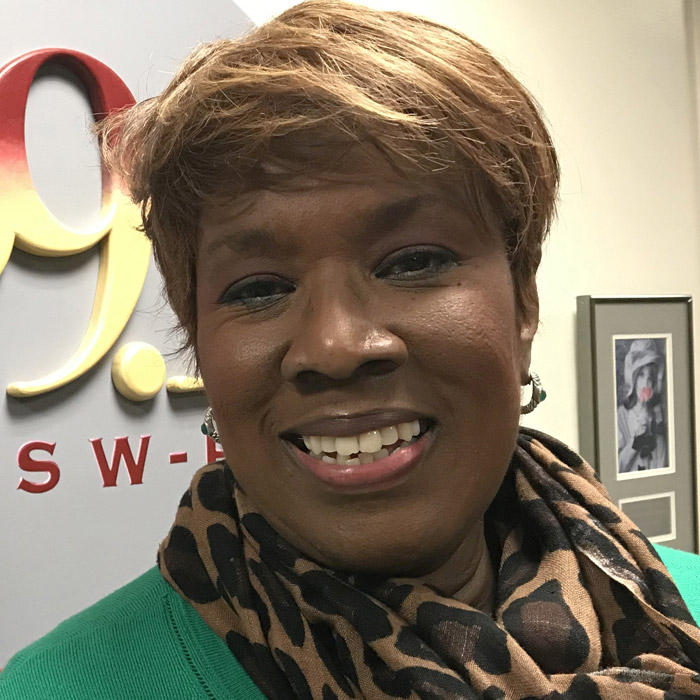 Gina with green sweater and leopard print scarf, smiling