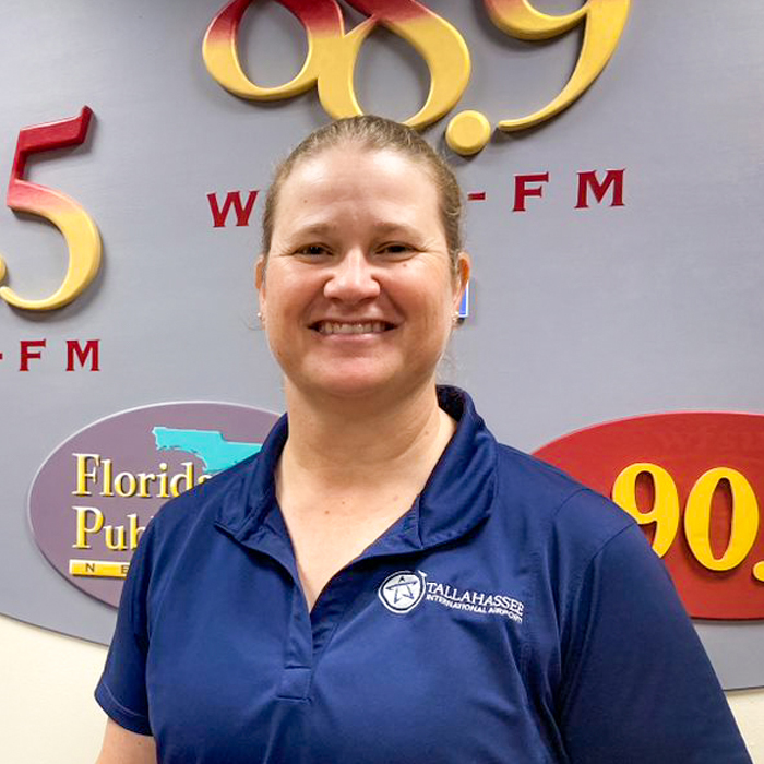 A smiling woman in a blue shirt smiles.