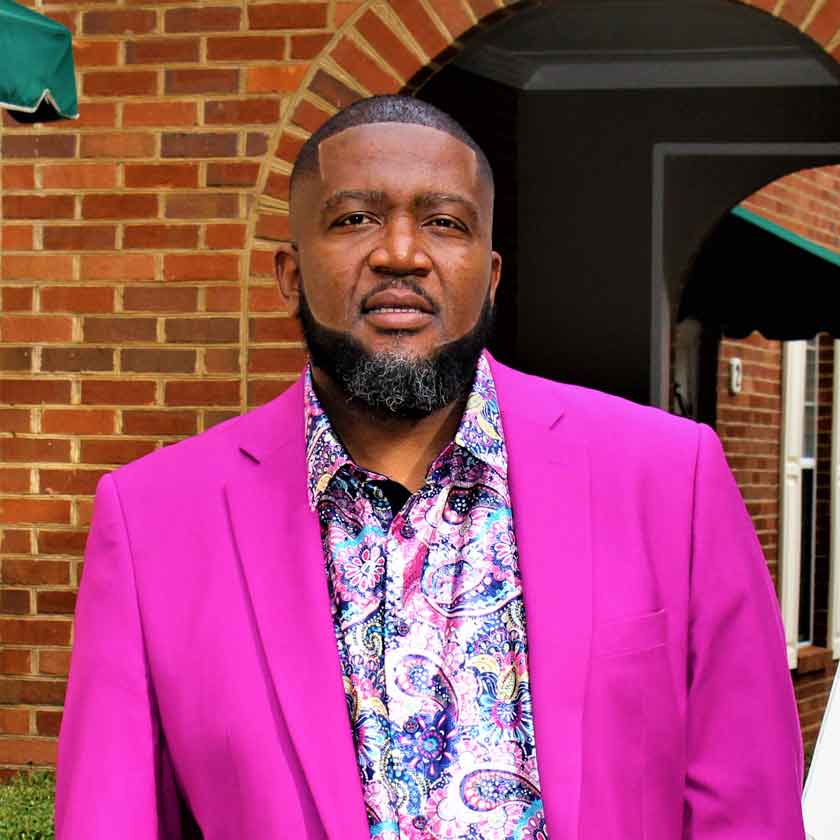 A man in a fuchsia blazer stares forward. 