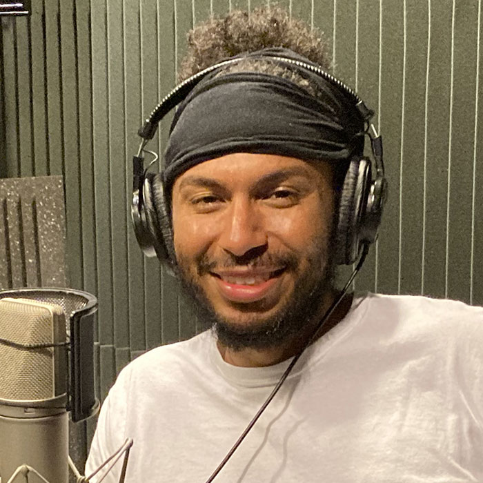 A smiling man sits in front of a microphone.