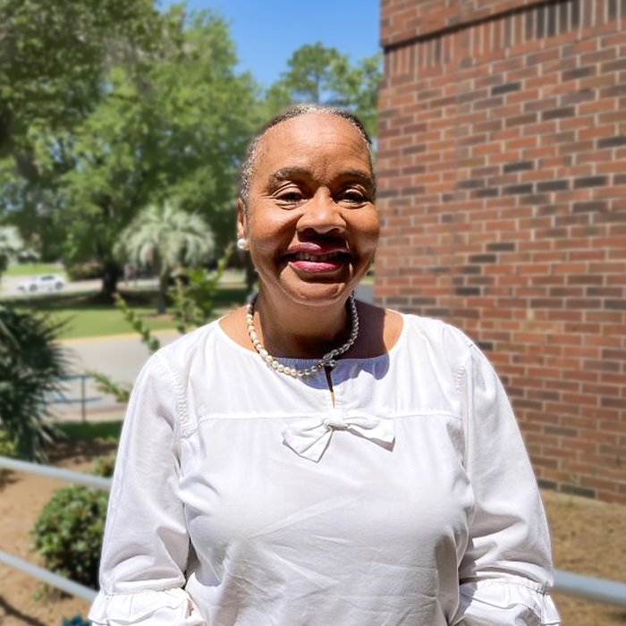 A smiling woman stands outside