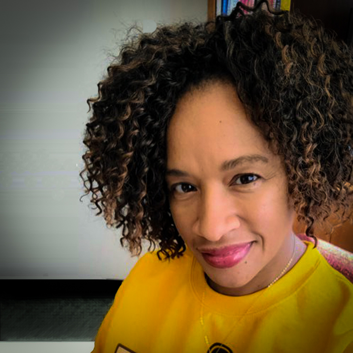 A smiling woman in a yellow shirt stares forward.