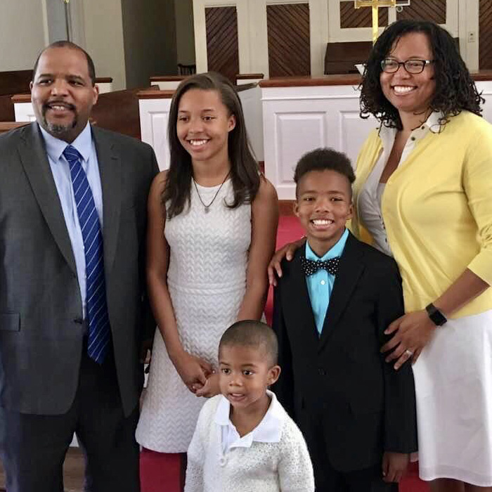 parents, a young girl and two boys standing together at a church