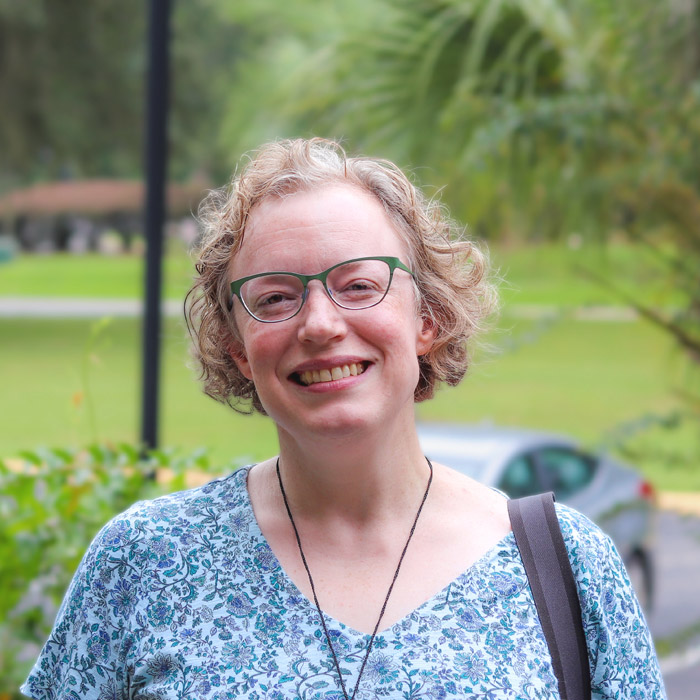 A woman in blue smiles and stares forward.