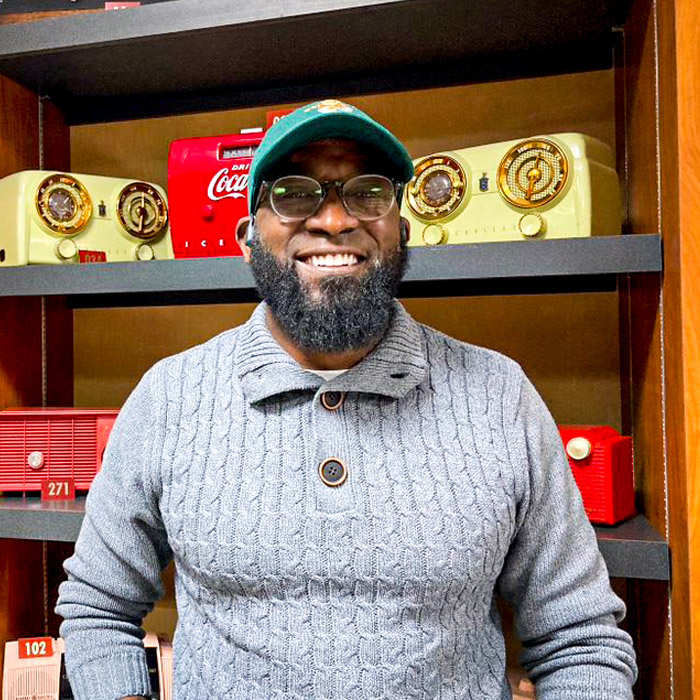 A smiling man stand in front of a radio collection.