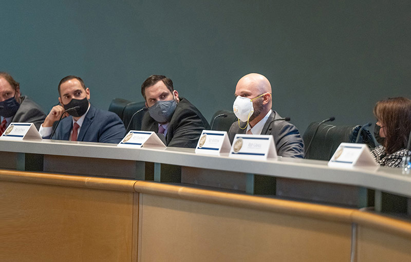 people sitting in a row behind a desk with microphones